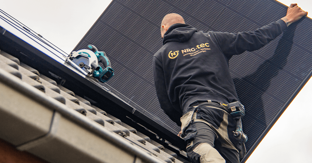 Installateur van NRG-TEC die zonnepanelen plaatst op een hellend dak in Lichtervelde.